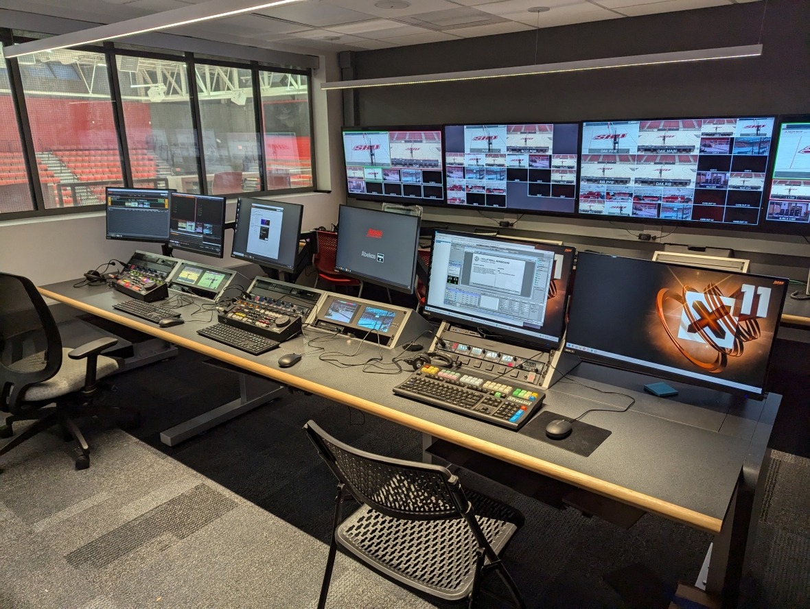 Sports arena control room with rows of screens and various control boards
