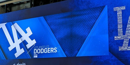 A large digital display screen hanging on the wall. The screen is showing the Los Angeles Dodgers branding.