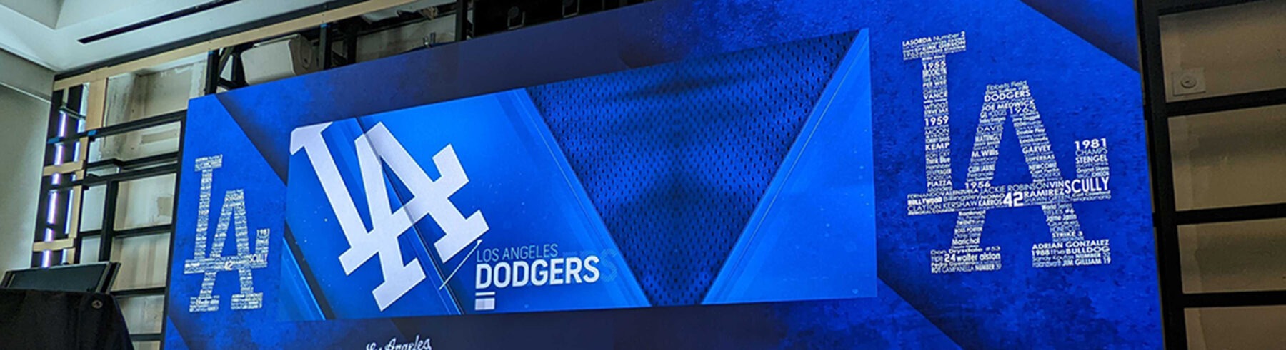 A large digital display screen hanging on the wall. The screen is showing the Los Angeles Dodgers branding.